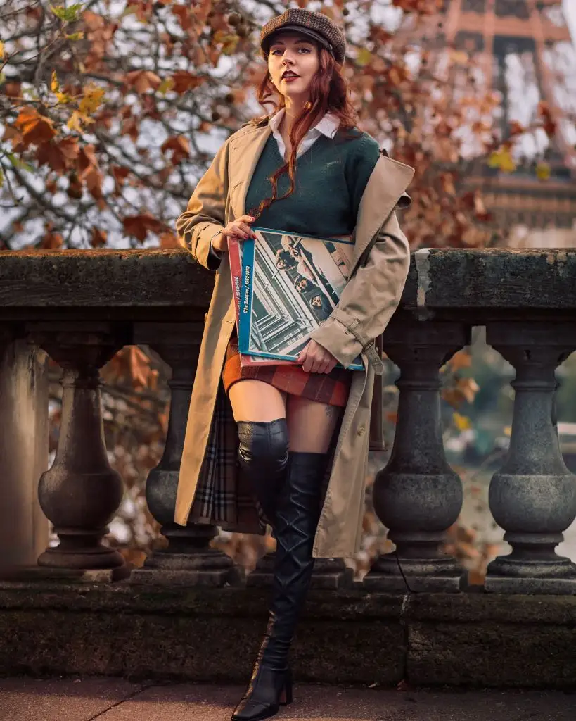 Beige trench coat with green sweater, plaid skirt, and black over-the-knee boots in Paris