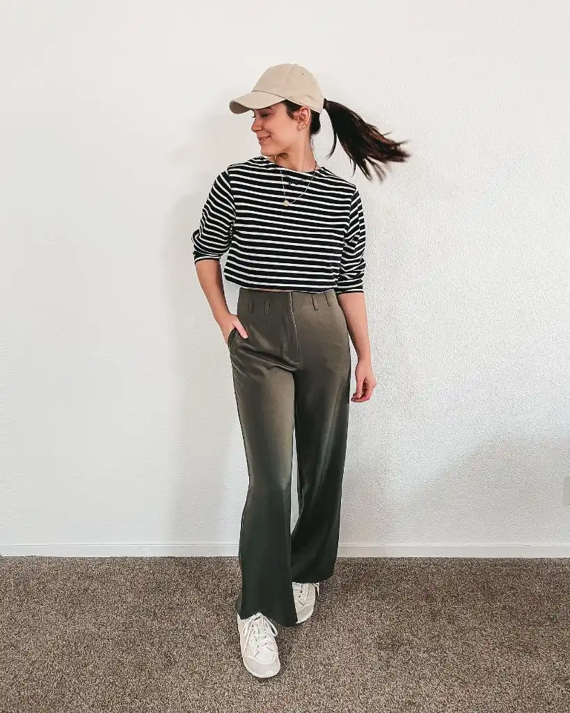 Black and white striped long-sleeve top with olive wide-leg trousers, beige cap, and white sneakers