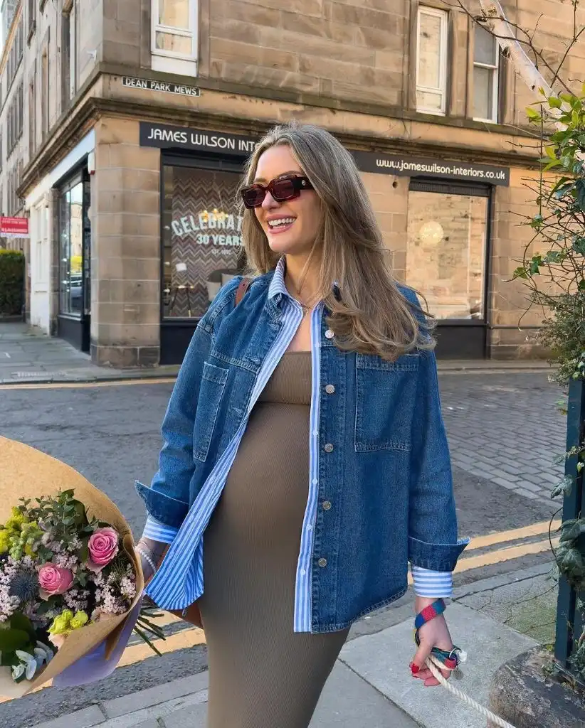 Pregnant woman wearing denim shacket over ribbed tan midi dress with flowers and sunglasses