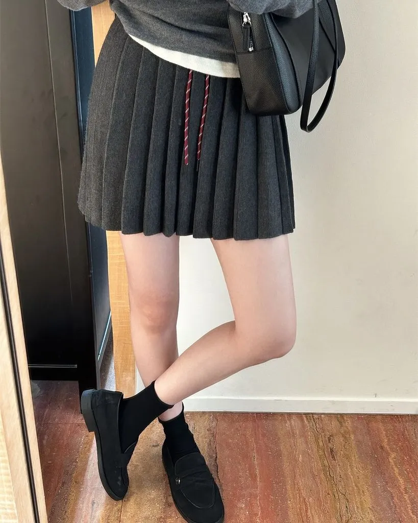 Dark grey pleated knit mini skirt with grey sweater and loafers