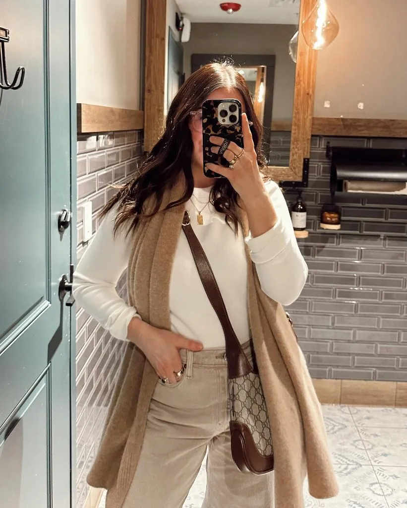 Mirror selfie with camel scarf draped over white top and beige jeans
