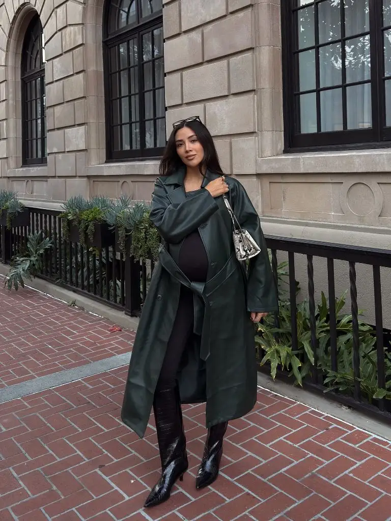 Pregnant woman in dark green leather trench coat, black bodycon outfit, croc boots, and snakeskin bag