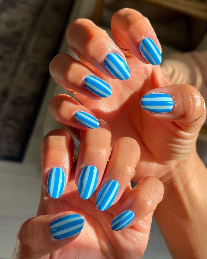 Blue and white vertical striped nails on short oval nails August nails color 2026 ideas