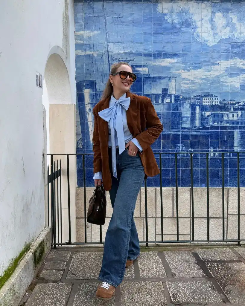 Brown suede blazer with blue bow blouse and wide-leg jeans in front of azulejo tiles