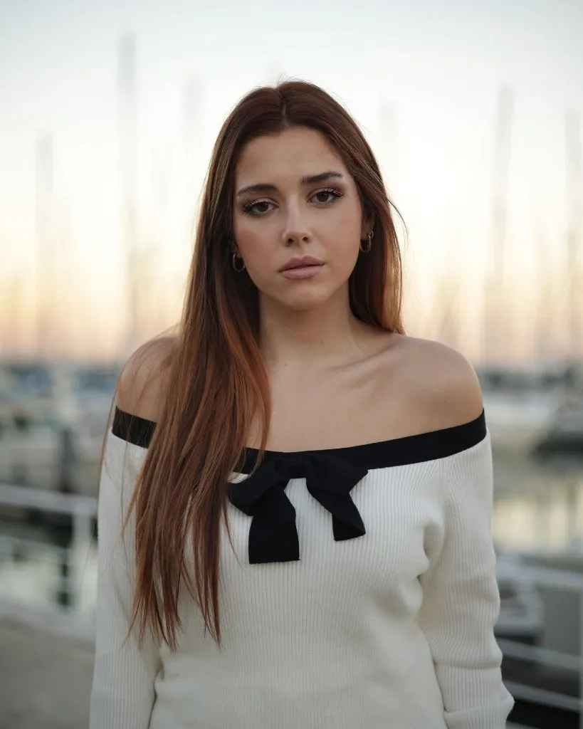 Off-shoulder white sweater with black bow detail at marina