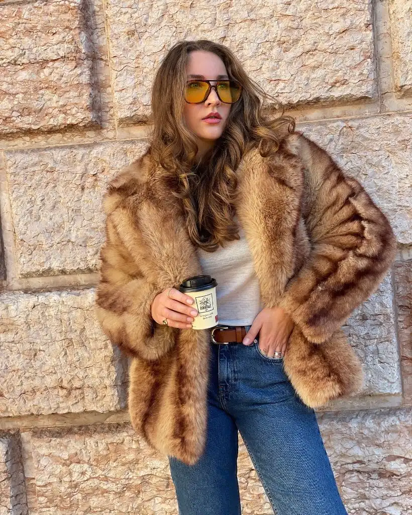 Brown fur coat over white top and jeans with coffee