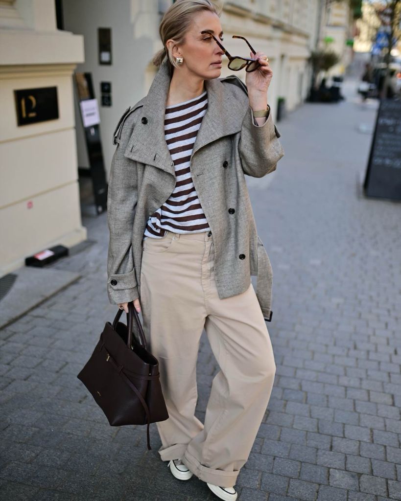 Grey short peacoat over brown and white striped top with beige wide pants