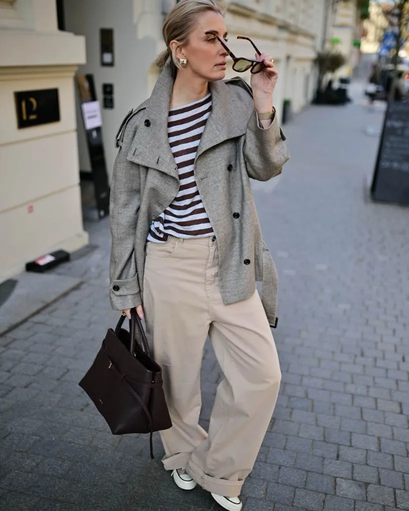 Grey short peacoat over brown and white striped top with beige wide pants