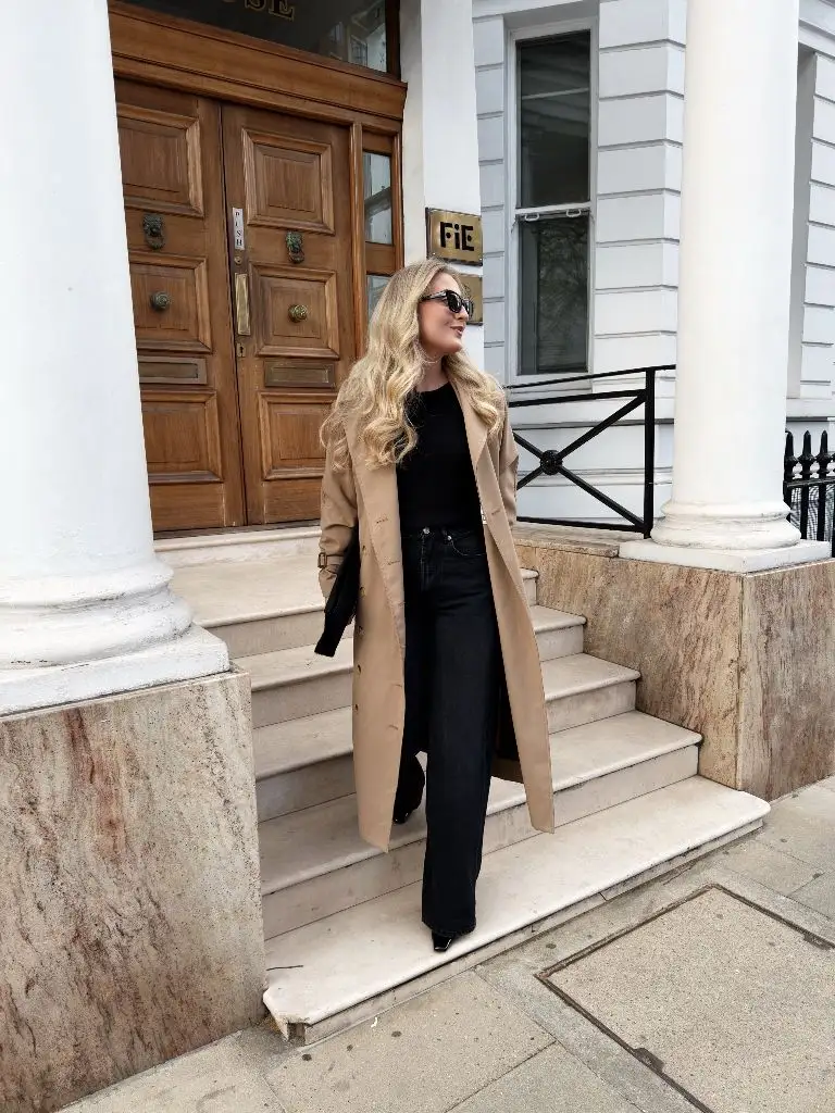 Camel coat with all-black outfit descending steps in London