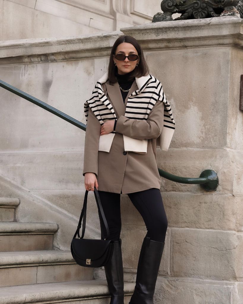 Taupe blazer with striped sweater draped over shoulders and black leggings