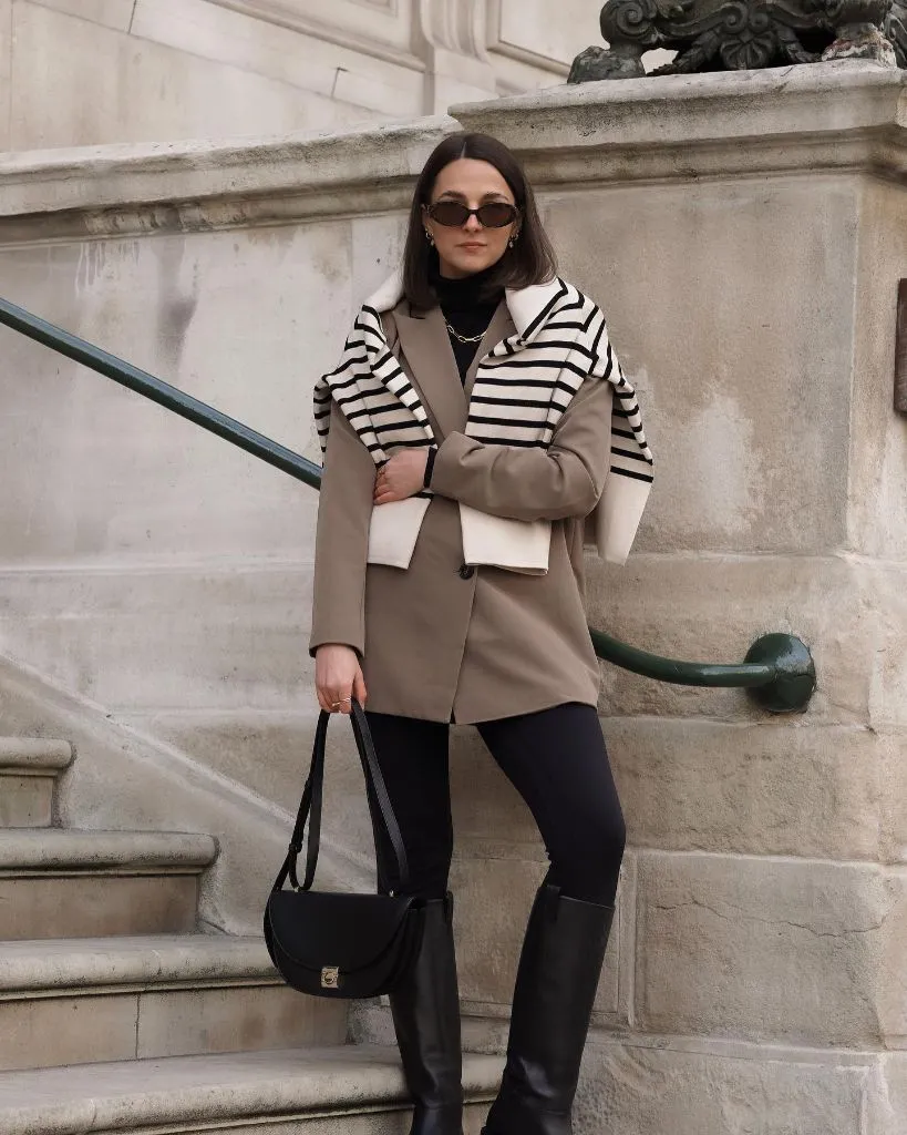 Taupe blazer with striped sweater draped over shoulders and black leggings