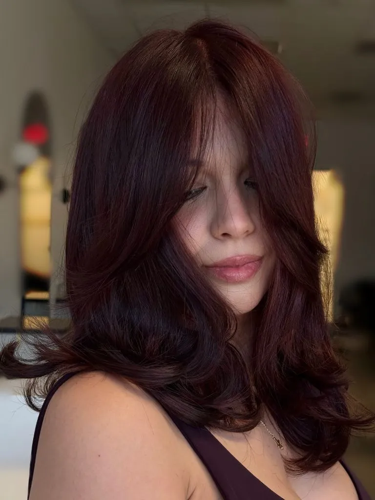 Layered mahogany red hair with face-framing curtain layers