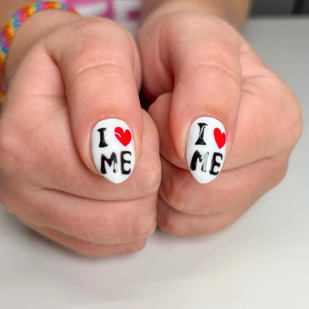 I love me text nail art with red hearts on short white nails August nails color 2026 ideas
