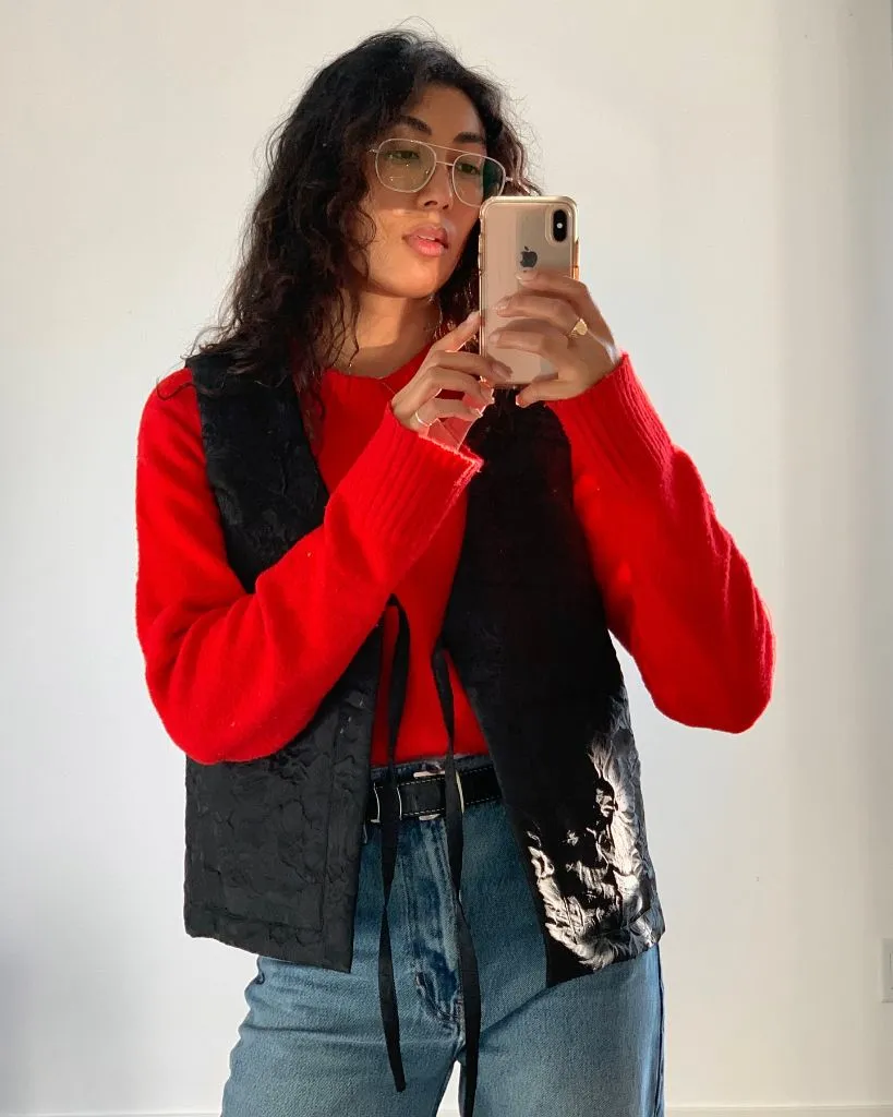 Red sweater with black quilted vest and jeans