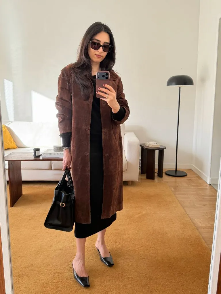 Brown suede coat over black outfit with structured bag and mules