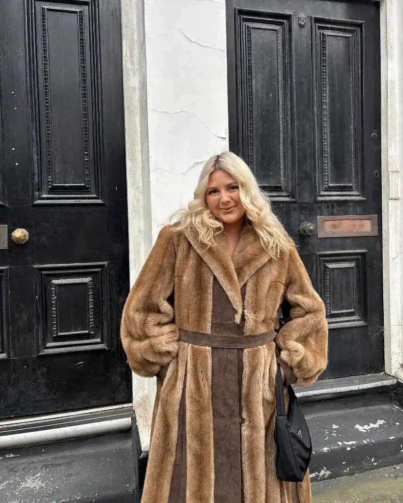 Camel and brown faux-fur long coat in front of black doors