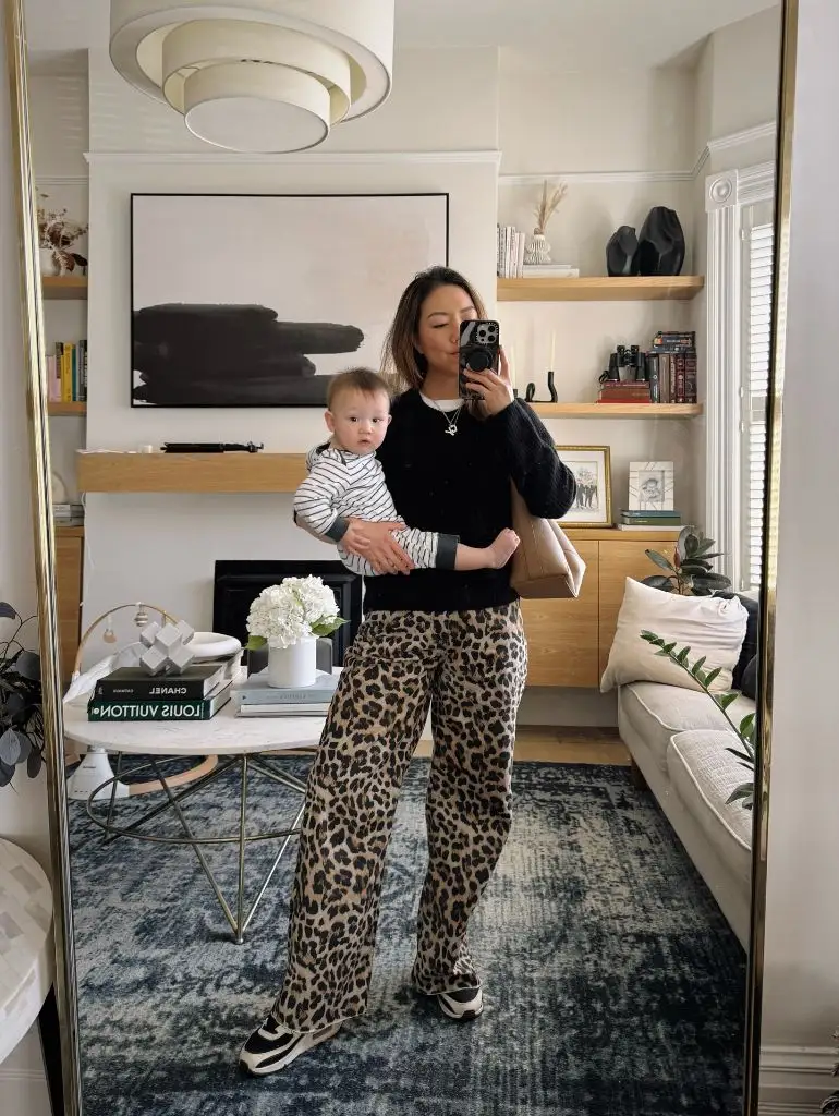 Mirror selfie with baby in black top and leopard print pants