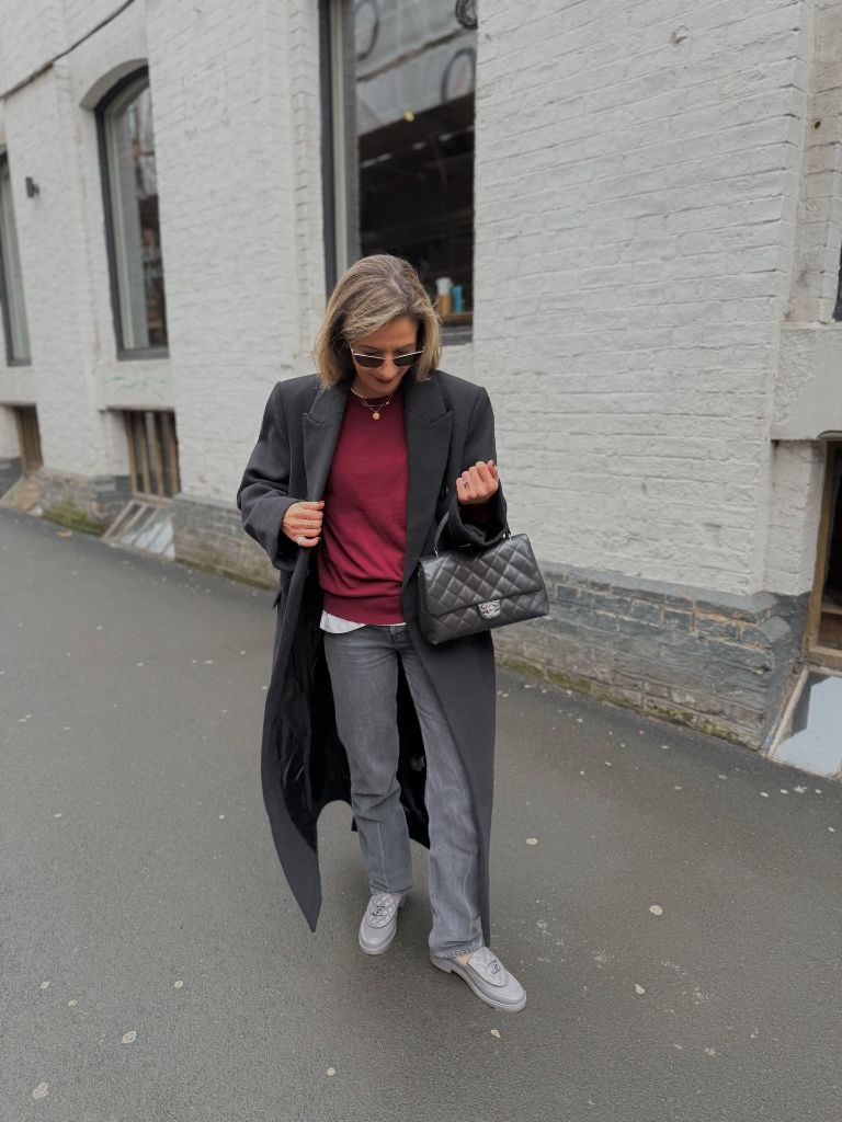 Dark grey long coat over burgundy sweater with grey jeans and Chanel bag