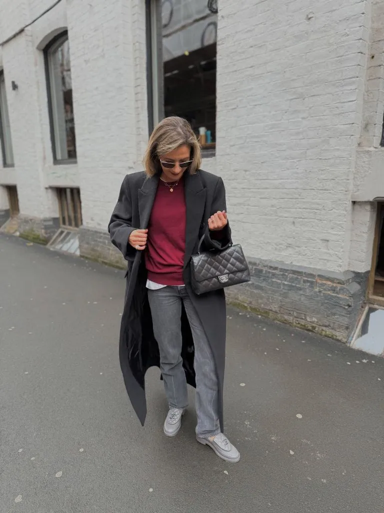 Dark grey long coat over burgundy sweater with grey jeans and Chanel bag