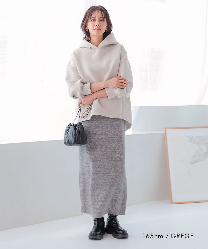 Woman in cream hoodie, grey knit maxi skirt and black chunky boots