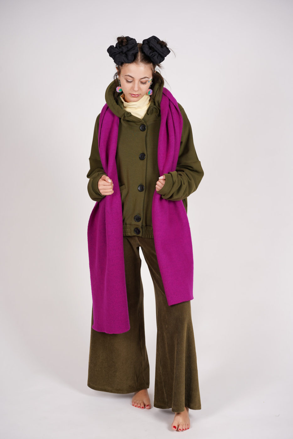 Woman in an olive green hooded wool coat with a beige turtleneck, olive corduroy wide-leg pants, and a magenta scarf