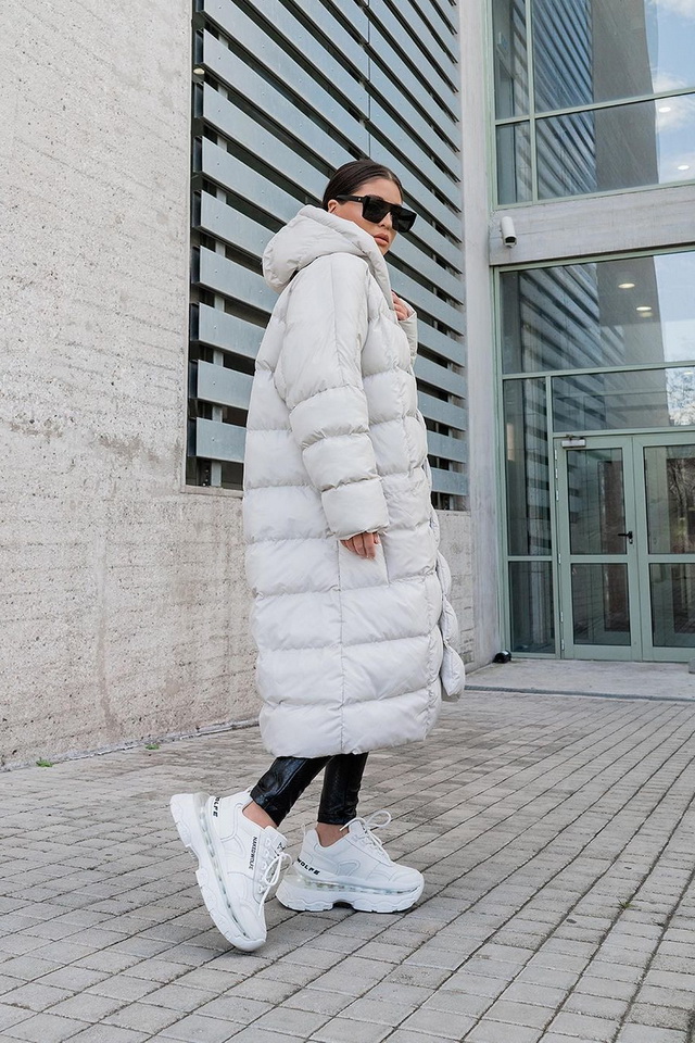 Woman in a long white puffer coat with black leggings and white chunky sneakers