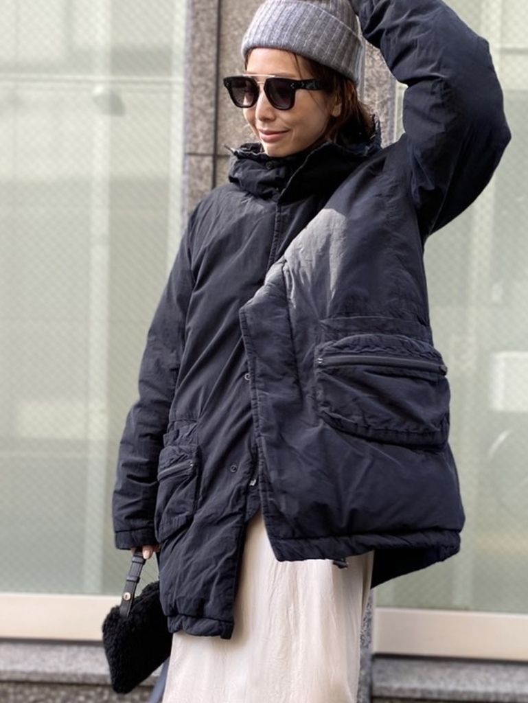 Woman in an oversized black puffer parka with a cream maxi skirt and beanie
