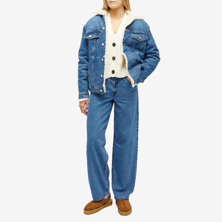 Woman wearing a sherpa-lined denim trucker jacket with wide-leg jeans