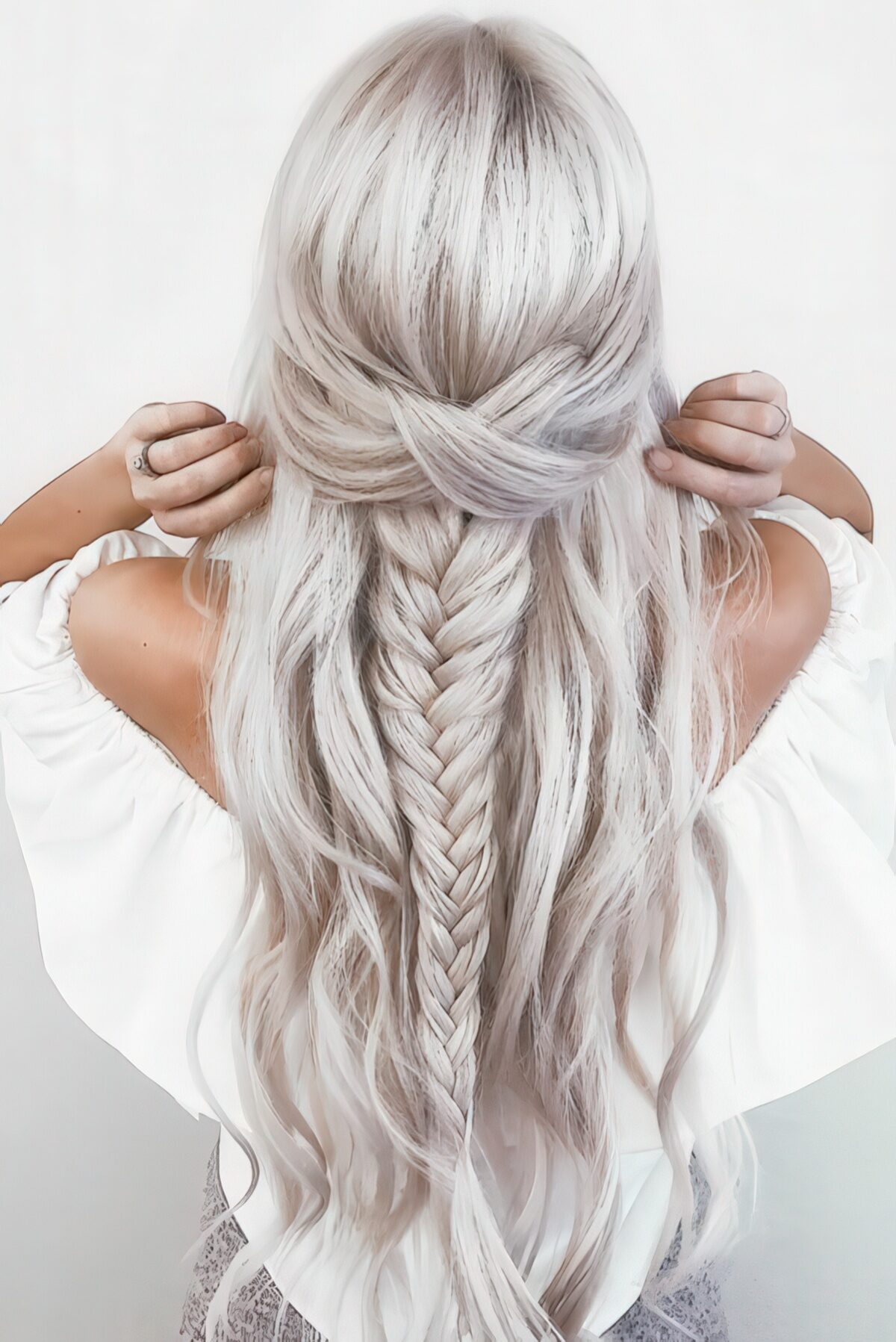 Half-up fishtail braid on long platinum-blonde wavy hair with twisted face-framing sections