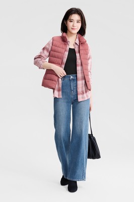 Woman in a dusty-rose quilted vest over a pink plaid flannel shirt with medium-wash wide-leg jeans