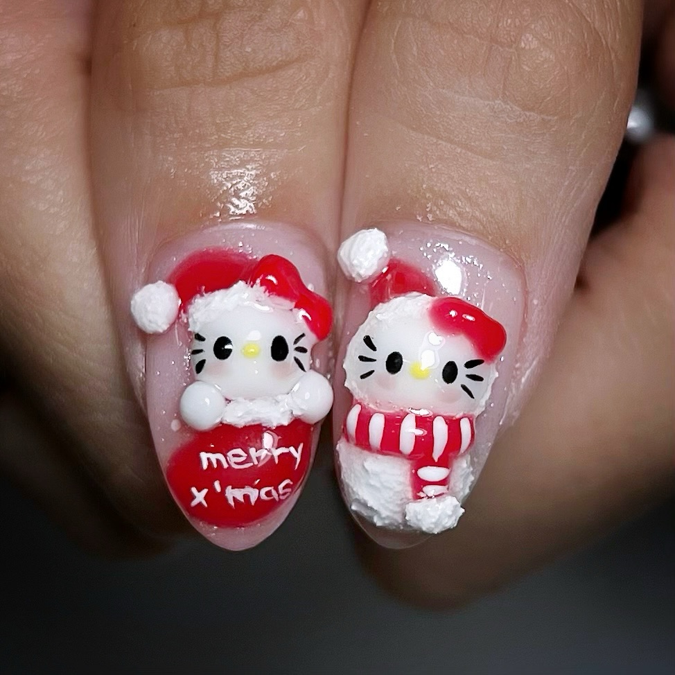Two short almond nails with 3D sculpted Hello Kitty in a Santa suit, merry Christmas lettering and textured snow
