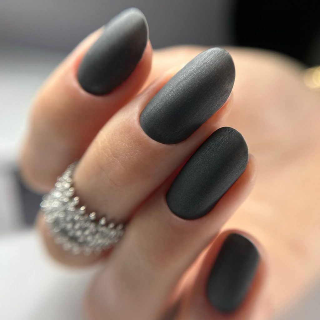Almond nails in a soft matte charcoal-grey crème; real photography.