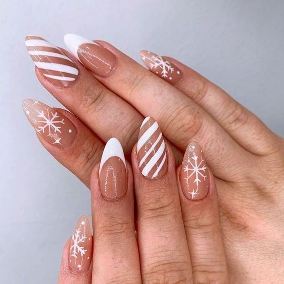 Nude almond nails with white French tips, candy-cane stripes and snowflake art
