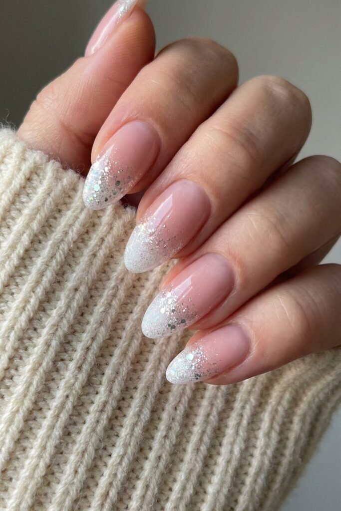 Almond nails with sheer pink base and silver glitter faded tips