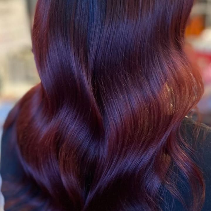 Long wavy dark plum-red hair with warm copper undertones