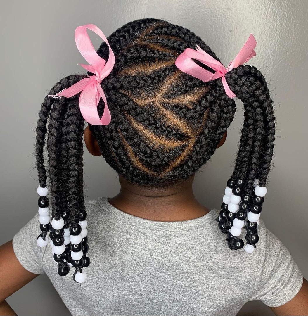 Two braided pigtails with pink satin bows and black-and-white beads