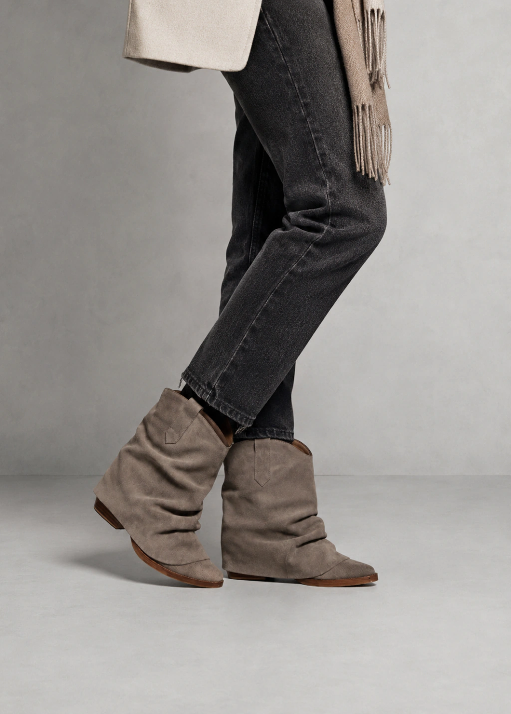 Woman in grey slouchy western-style boots with black jeans, fringe scarf and light jacket