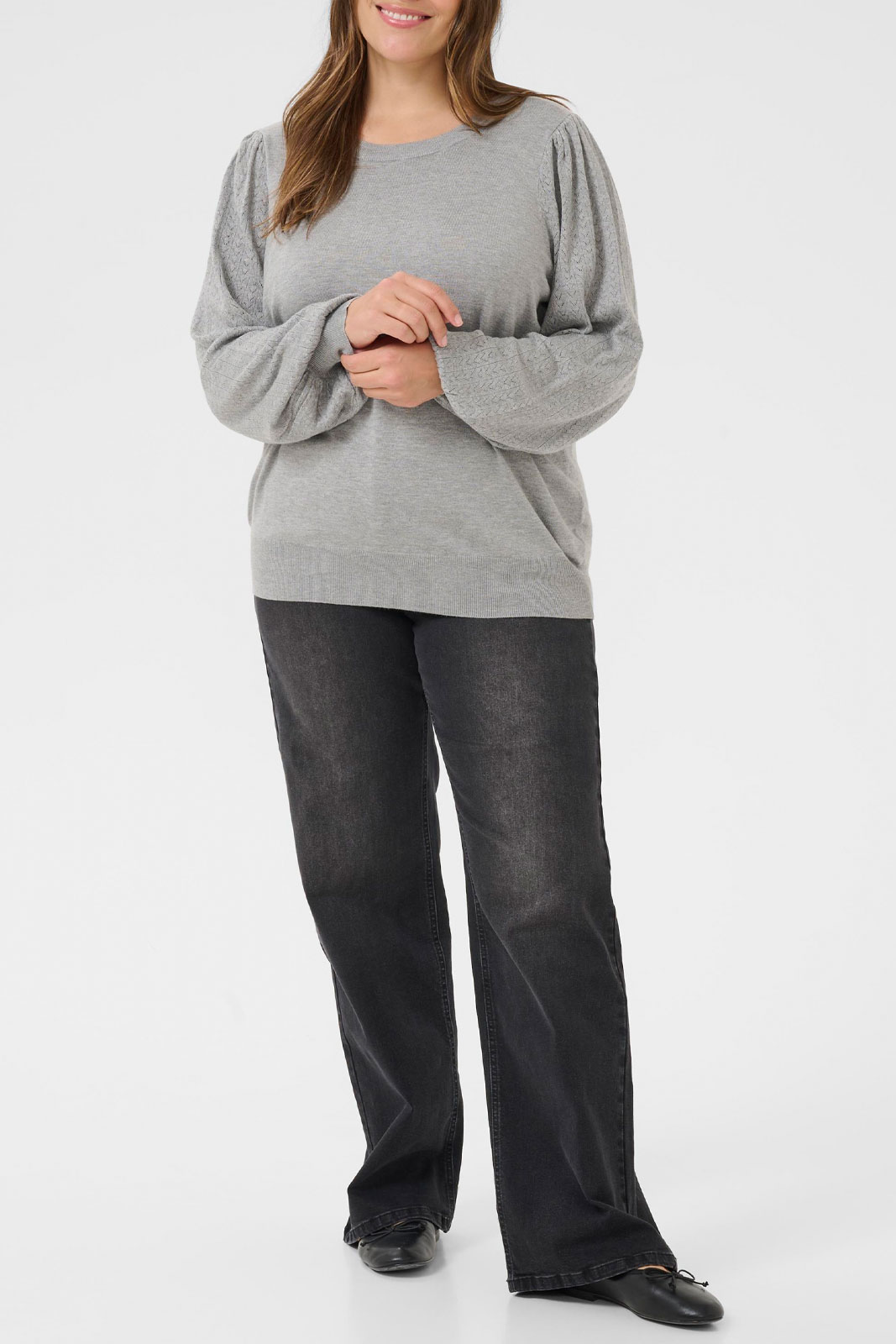 Woman in a light-grey balloon-sleeve knit with dark wide-leg jeans and black flat shoes