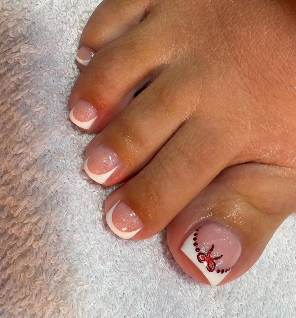 White French tip pedicure with a small red bow and dotted arc on the big toe
