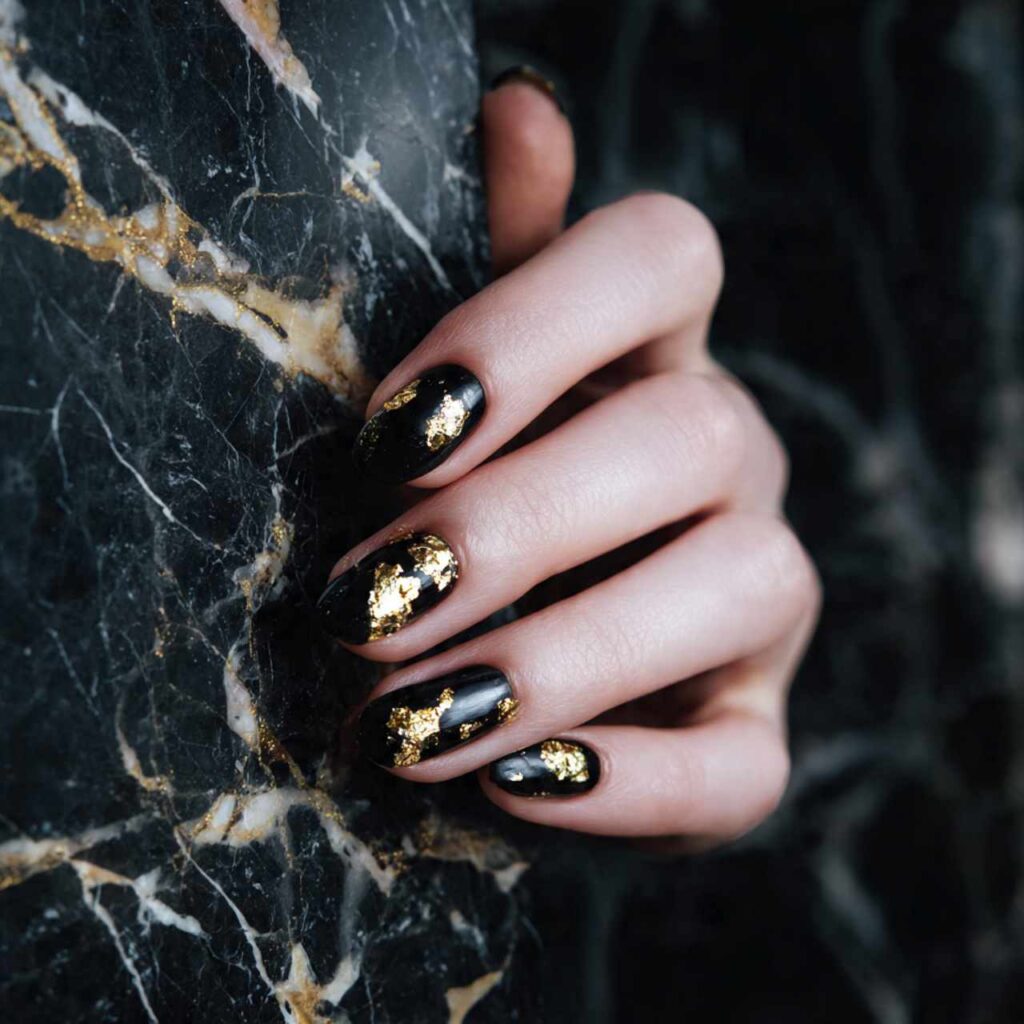 Glossy Black with Gold Foil Flakes: glossy black short oval nails with chunky gold foil flakes