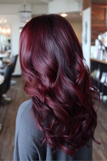 Dark cherry burgundy wavy lob in a salon, back view