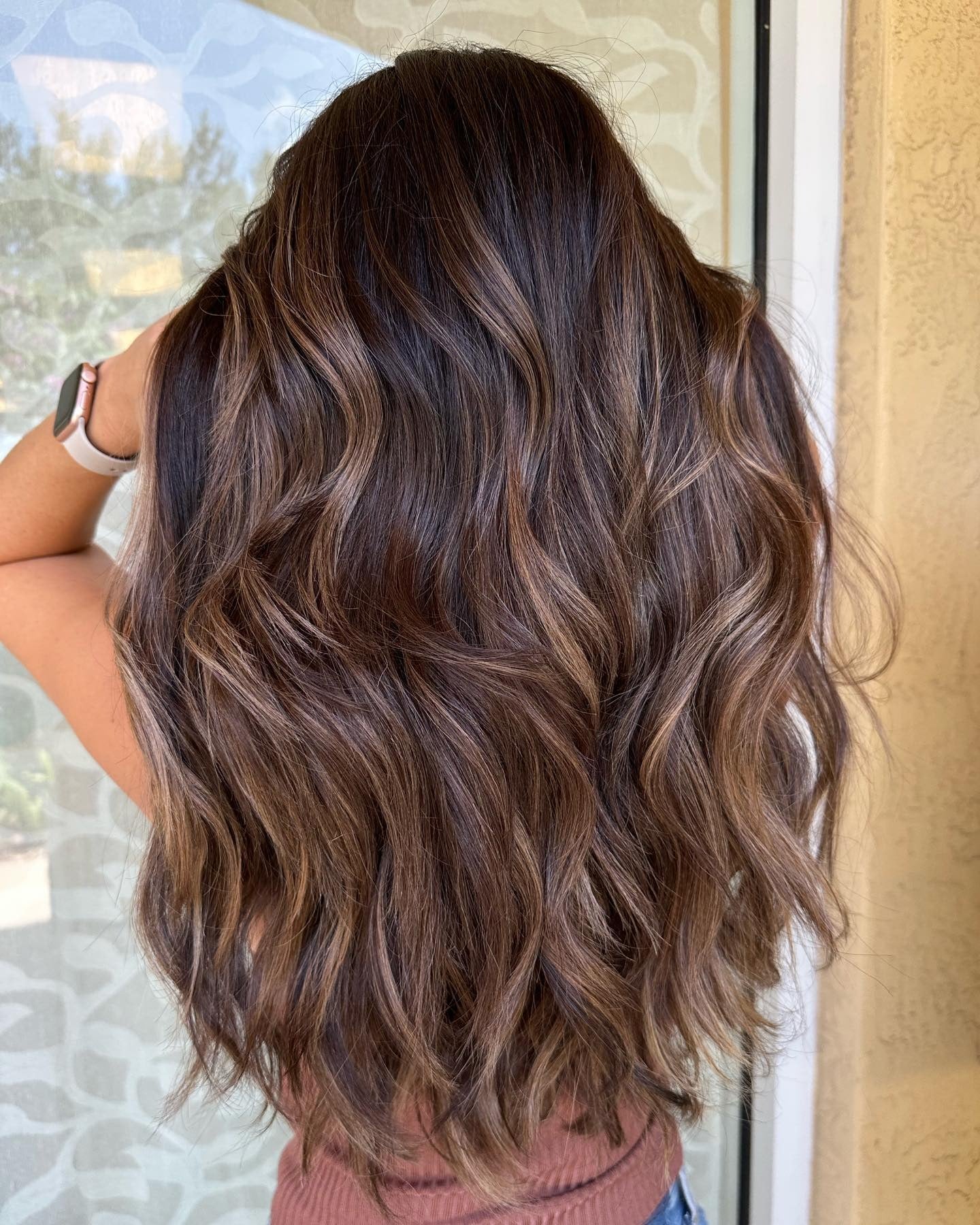 Back view of rich brunette wavy hair with warm toffee balayage texture