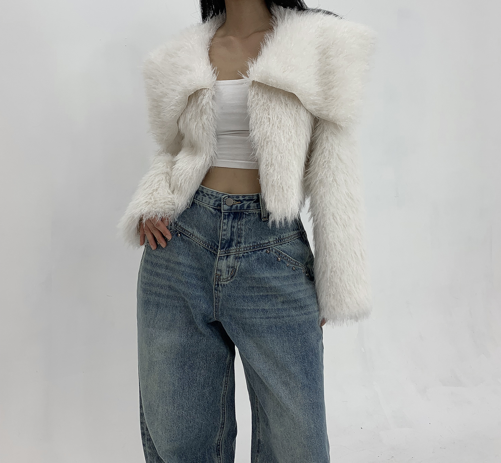 Woman in cropped white faux fur jacket with high-waisted jeans