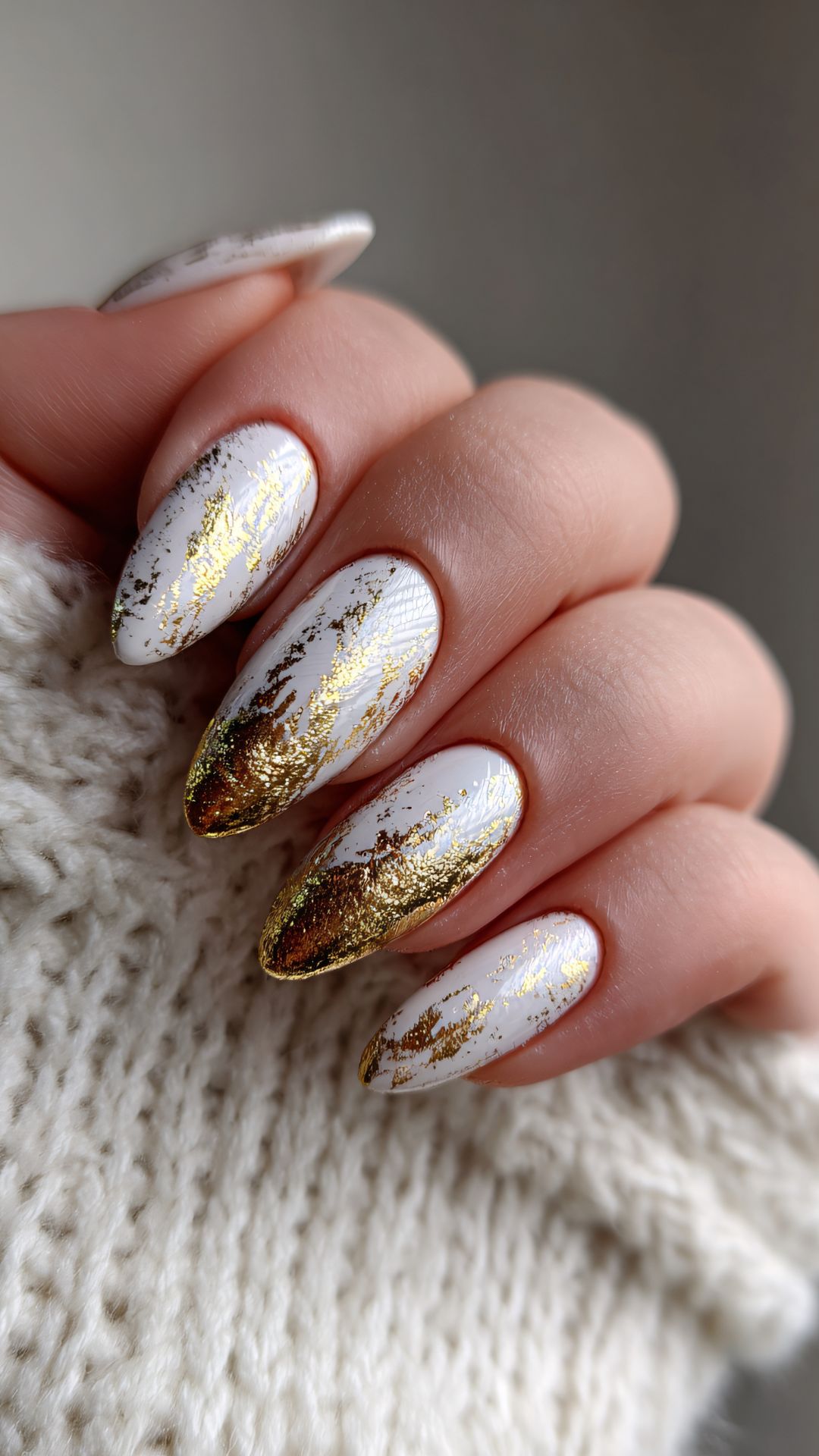 White stiletto nails with gold foil accents near the tips