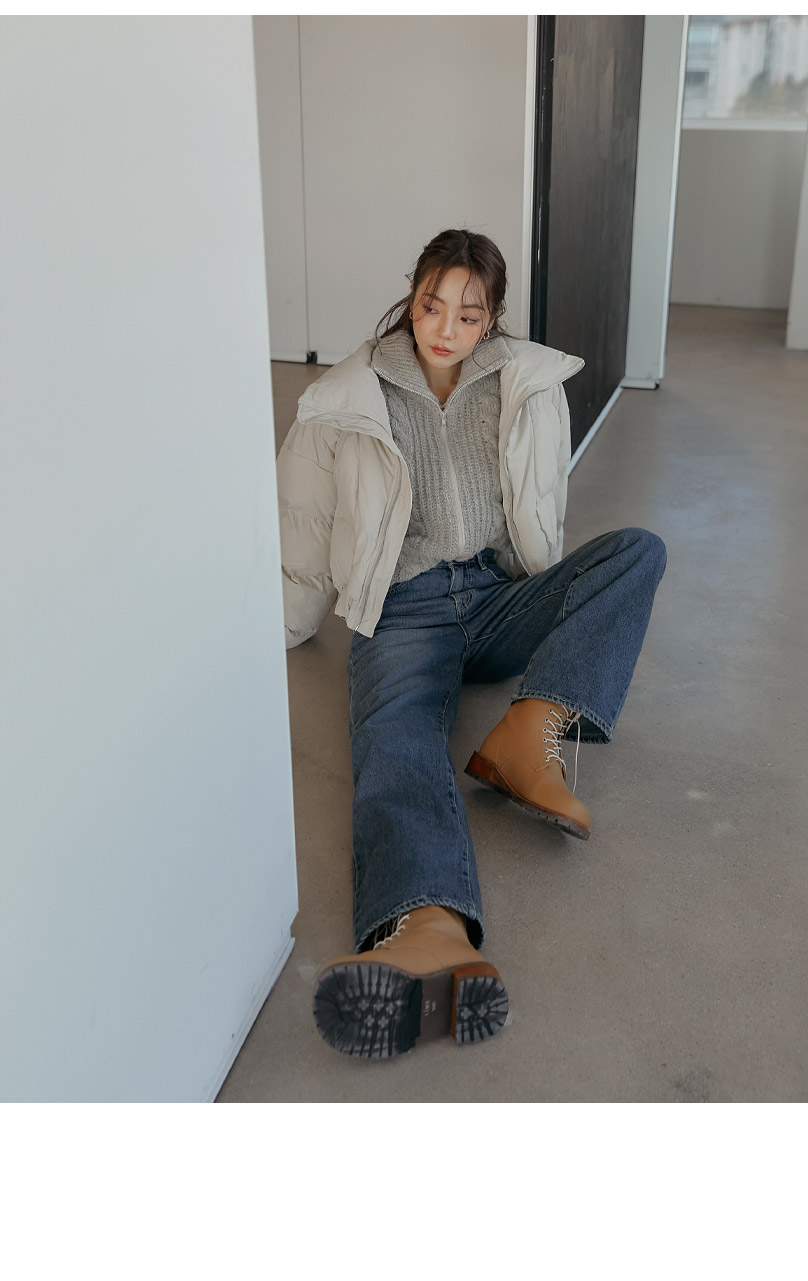 Woman in a cropped cream puffer over a grey ribbed knit with medium-wash wide-leg jeans and tan lace-up boots