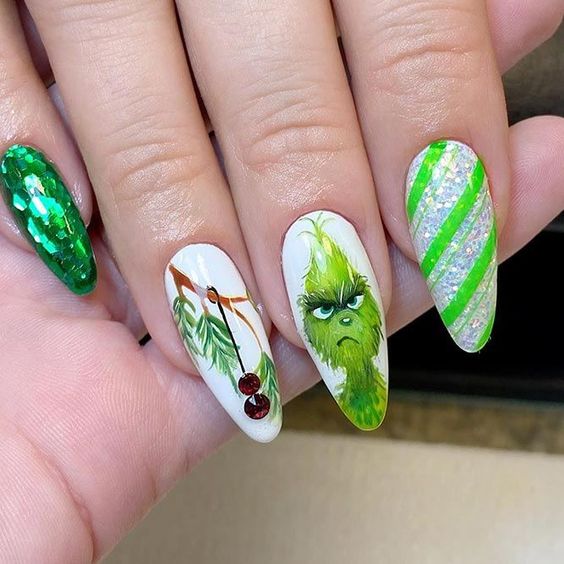 Long almond nails with a hand-painted Grinch face and red glitter accents