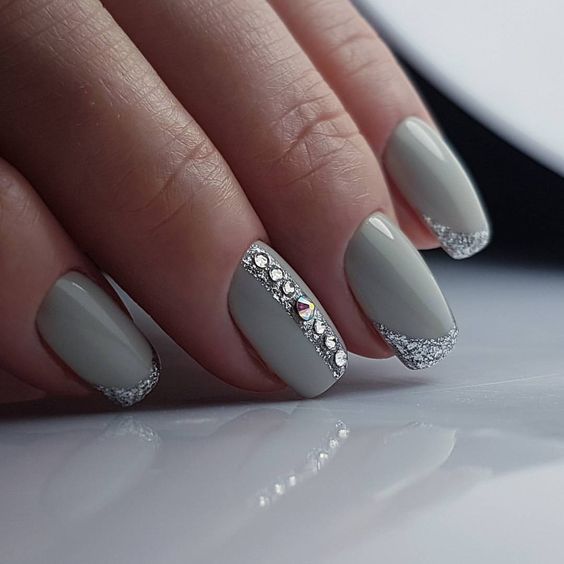 Medium oval nails in soft grey with a rhinestone band down one nail and silver glitter French tips