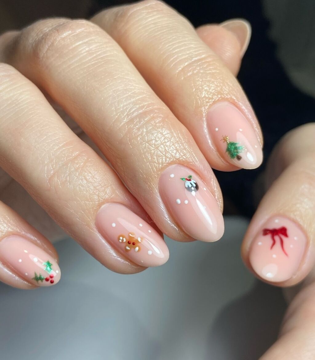 Blush nude nails with tiny Christmas icons like a tree, holly, bow and ornament