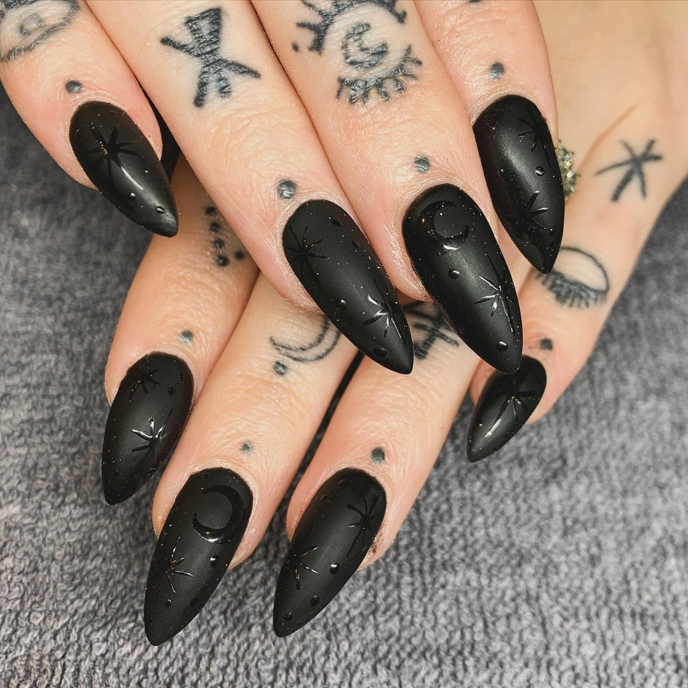 Matte black almond nails with glossy black moon and star details