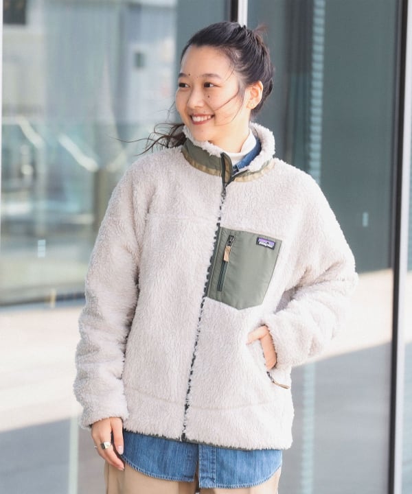 Woman in a cream fleece jacket with an olive contrast chest pocket layered over a denim shirt